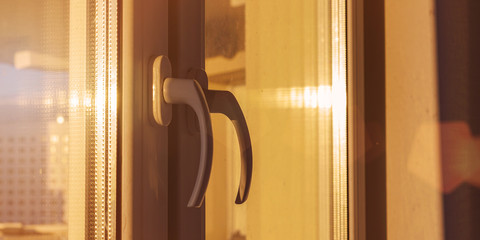close-up plastic handle of modern window with bright ray of sun