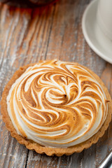 Close up of tartlet with lemon curd and burnt meringue, served with a cup of black tea