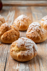 Close up of golden crust profiterole stuffed with buttercream on vintage wooden table