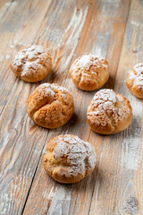 Golden crust profiterole stuffed with buttercream on vintage wooden table