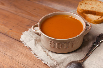 Bowl of carrot soup with vegetable bread and spoon on wooden background. Homemade healthy baby food, ready to eat. Easy home cooking. 