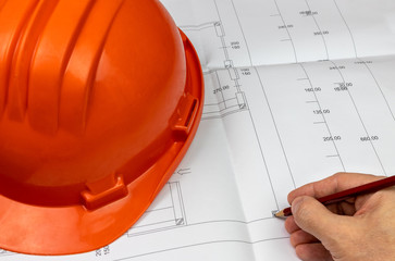 hand drawing building construction project, with orange helmet resting on the left
