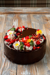Brightly decorated chocolate birthday cake with icing, cream chamomile and strawberry