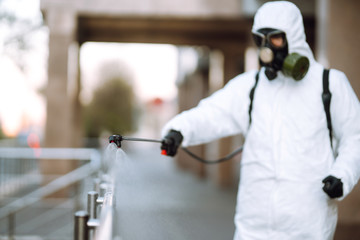 Disinfectant sprayers with spray chemicals onto the railing in the empty public place at dawn in the city of quarantine. Covid -19. Cleaning concept.