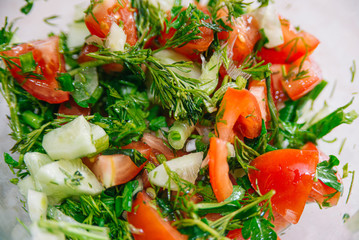 Spring or summer salad with fresh vegetables, tomatoes and cucumber in a bowl on a white background. Healthy raw food and vegetarian concept