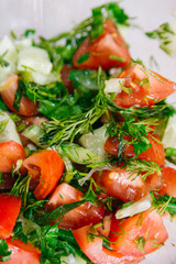 Spring or summer salad with fresh vegetables, tomatoes and cucumber in a bowl on a white background. Healthy raw food and vegetarian concept