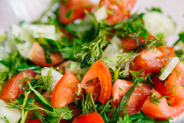 Spring or summer salad with fresh vegetables, tomatoes and cucumber in a bowl on a white background. Healthy raw food and vegetarian concept