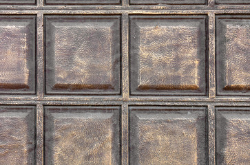 The texture of the concrete wall under the stylization of bronze metal squares.