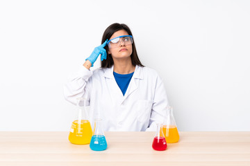 Young scientific woman in a table making the gesture of madness putting finger on the head