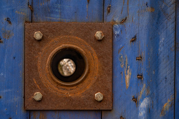 Old wood with blue paint and rusty plate with axis hole.