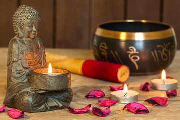 stone sitting buddha, candles and Tibetan bowl. Around the candle, the atmosphere for meditation....