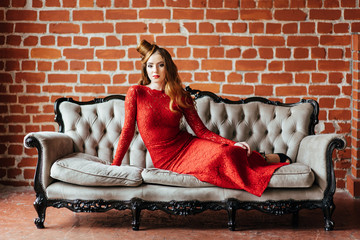 Obraz premium young girl with red hair in a bright red dress in a bright room
