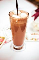 Glass cup of cocoa with marshmallows on wooden table
