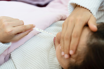 Sick woman with thermometer is lying in bed. She has cold, flu and high fever. concept of disease and ill