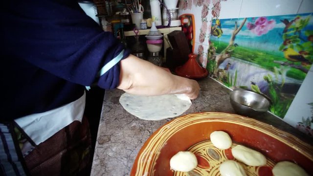 Moroccan woman making a dough using her hands on a marble counter. the most traditional Moroccan dishes.