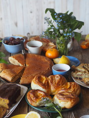Food background. Home baking buns, cakes and forget-me-not flowers on a wooden table with food.
