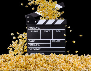 Flying popcorn and film clapper board isolated on black background