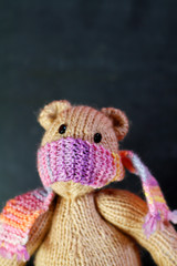kleiner gestrickter Teddybär, mit Mundschutz, Gesichtsmaske zum Schutz vor Corona, vor schwarzer Tafel.