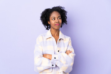 Young African American woman isolated on purple background looking to the side