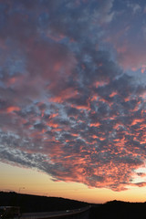 Romantic sunset atmosphere with gray-orange clouds. Highway silhouette with rare cars