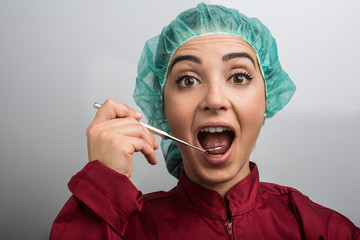 dentista con cuffietta verde in testa e camice rosso ci mostra scherzosamente come si controlla un...