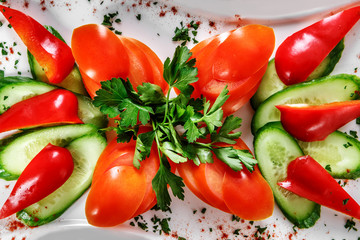 Sliced tomatoes, cucumbers and parsley on a plate sprinkled with spices