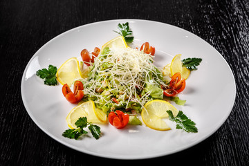Lemons, tomatoes, parsley lettuce leaves are spread out on a platter