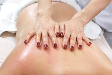 Cosmetologist gives a back massage to a woman