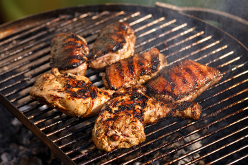 grilled duck breast fillets and chicken drumsticks on barbecue