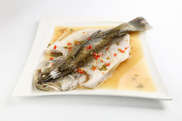 Thai style steam sea bass barramundi with lemon garlic chilli clear sauce on white serving dish