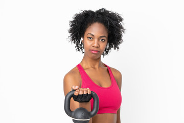 Fototapeta na wymiar Young African American woman isolated on white background making weightlifting with kettlebell and looking to the front