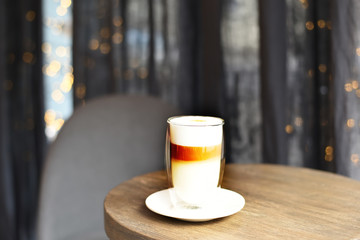 A glass of coffee with layers of whipped milk on a table. Selective soft focus.
