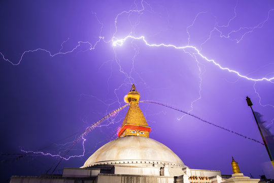 A thunderstorm front rages over center of the Bouddnath stupa. Lightning strikes, fluttern flags - lungta and a stupa with night illumination are visible.