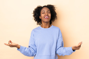 Young African American woman isolated on beige background in zen pose