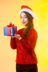 Giovane  mora vestita di rosso con cappello da babbo Natale, tiene in mano un pacco regalo che sta...