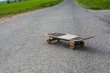Old skateboard stands on a lonely country road