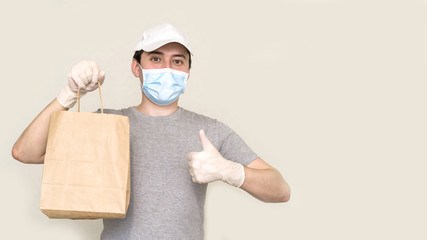 Fototapeta na wymiar Courier with a cardboard box in medical rubber gloves and a protective mask. Fast delivery by courier. Online shopping and Express delivery during the pandemic