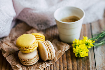 Obraz na płótnie Canvas Macarons saveur vanille et citron avec une tasse de café chaud sur une table en bois