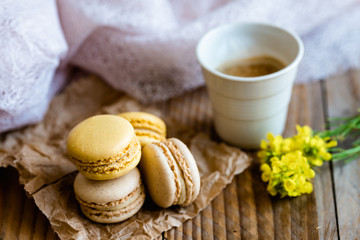 Macarons saveur vanille et citron avec une tasse de café chaud sur une table en bois