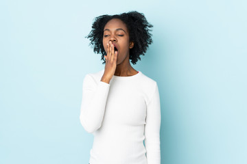 Fototapeta na wymiar Young African American woman isolated on blue background yawning and covering wide open mouth with hand
