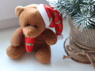 Teddy bear in a Christmas hat and scarf. Soft animal toys