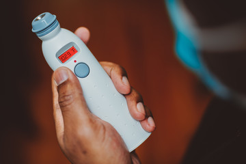 African american man using a temporal thermometer to record his temperature by running it across...