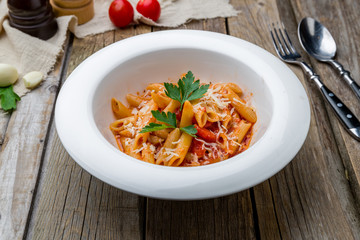 Pasta Penne arabiata on old wooden table