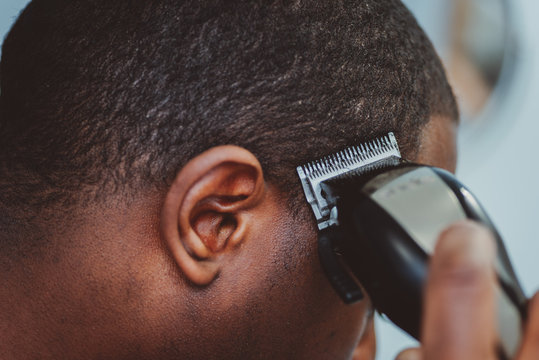 Personal hygiene, african american man cutting his own hair in the bathroom