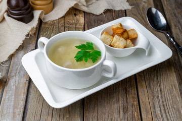Chicken soup bouillon in a plate on wooden table