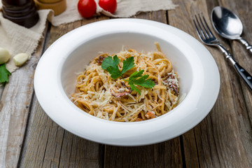 Spaghetti Carbonara with bacon on wooden table