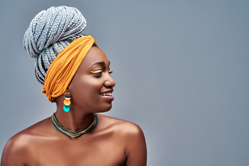 Close up view side portrait of cheerful young african woman smiling against gray background