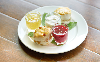 scone with pineapple jam and strawberry jam and cream in plate