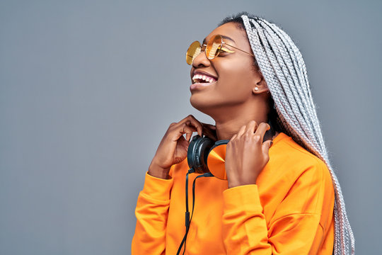 Close up side view portrait of afro american woman with sunglasses listening to music on earphones