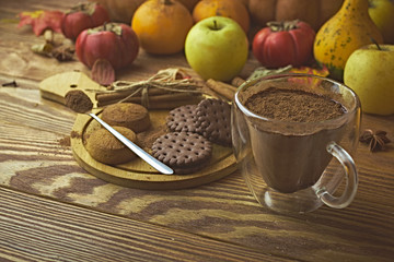 Chocolate cookies and cinnamon on the wooden plate with a glass of cacao and pumpkin with apples
